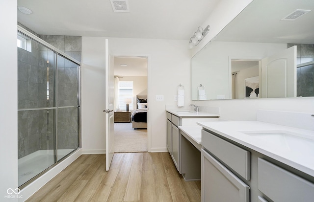 ensuite bathroom featuring ensuite bath, visible vents, wood finished floors, and a sink