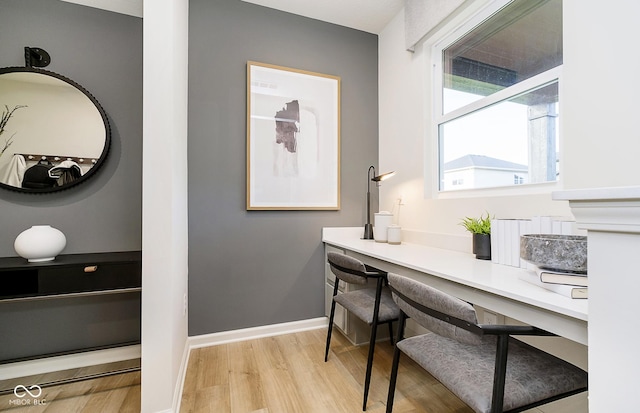 home office featuring built in desk, baseboards, and light wood-style floors