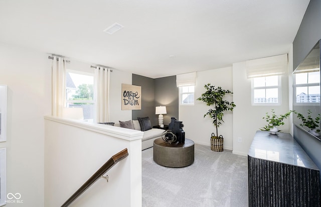 carpeted living room featuring visible vents, baseboards, and a healthy amount of sunlight
