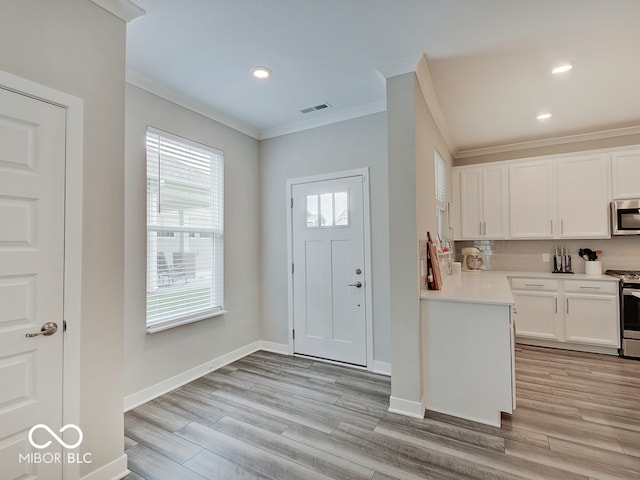kitchen featuring stainless steel appliances, white cabinetry, tasteful backsplash, visible vents, and ornamental molding