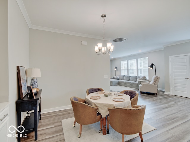 dining room with an inviting chandelier, crown molding, visible vents, baseboards, and light wood finished floors
