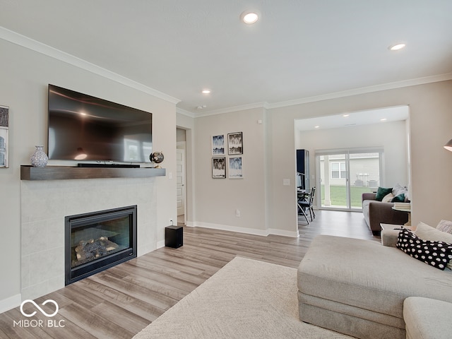 living room featuring crown molding, recessed lighting, baseboards, wood finished floors, and a tile fireplace