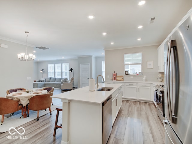 kitchen with stainless steel appliances, visible vents, ornamental molding, and a sink