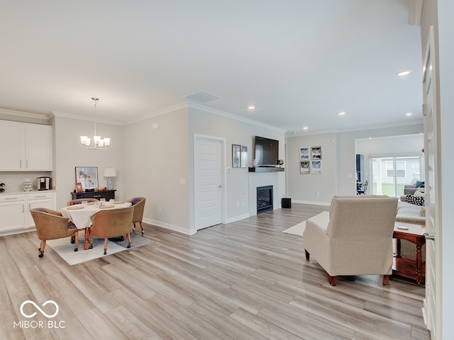 living room with recessed lighting, a notable chandelier, a glass covered fireplace, and light wood-type flooring