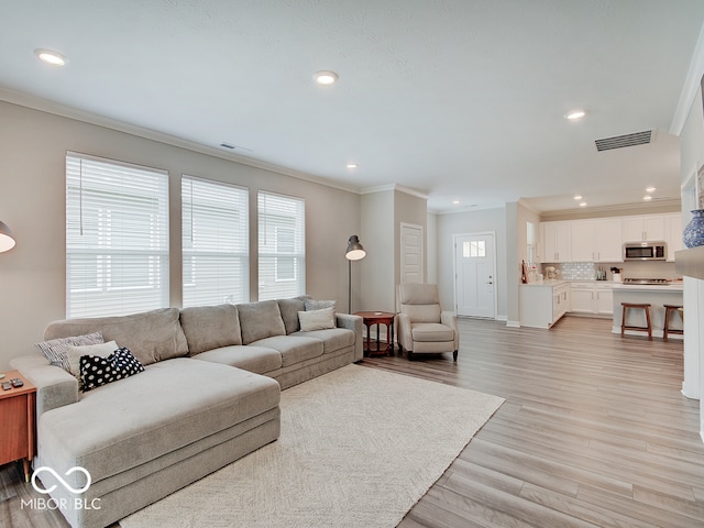 living room featuring crown molding, visible vents, and a wealth of natural light