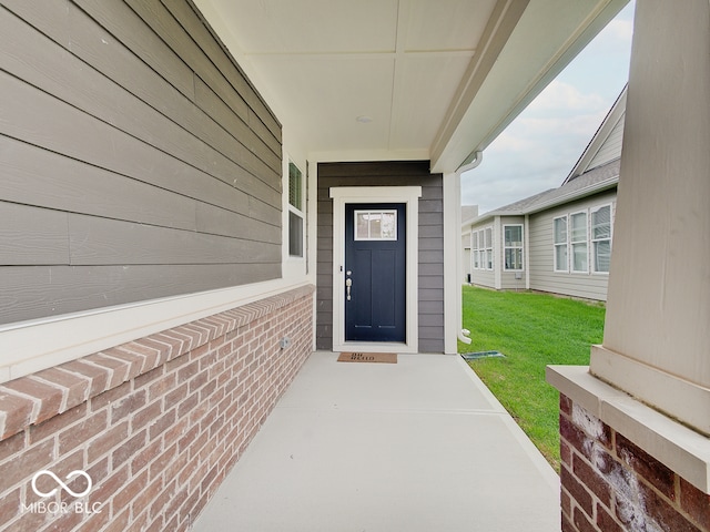 entrance to property featuring a lawn and a porch