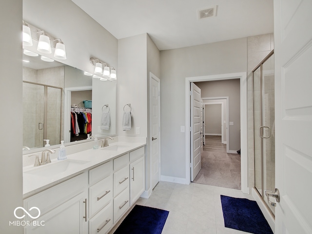 bathroom featuring visible vents, a sink, a walk in closet, and a shower stall