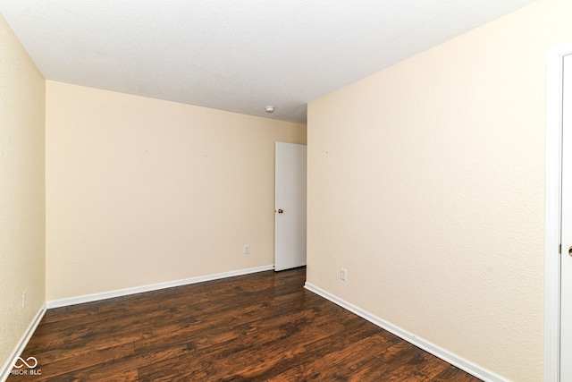 spare room featuring dark wood-style floors and baseboards