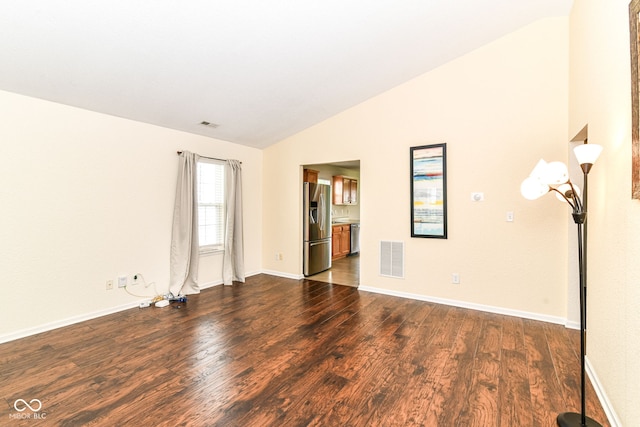 spare room featuring vaulted ceiling, dark wood-type flooring, and baseboards