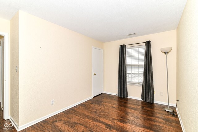 unfurnished room with dark wood-style flooring and baseboards
