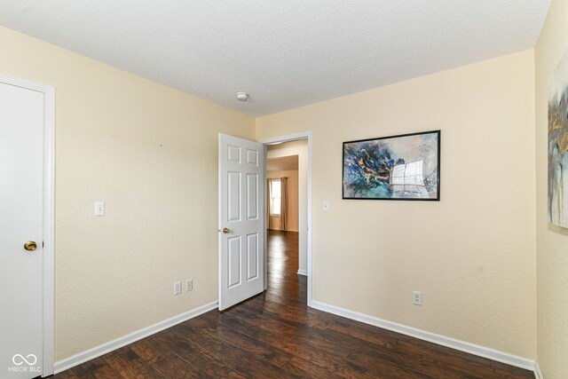 empty room featuring dark wood finished floors, baseboards, and a smoke detector