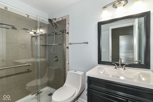 bathroom with a textured wall, toilet, a shower stall, and vanity
