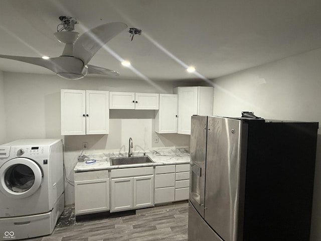 interior space featuring washer / clothes dryer, a ceiling fan, a sink, and light wood-style floors
