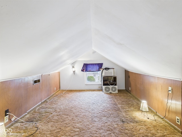 additional living space with carpet floors, wooden walls, and vaulted ceiling