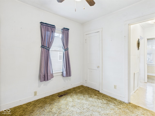 unfurnished room featuring carpet flooring, ceiling fan, visible vents, and plenty of natural light