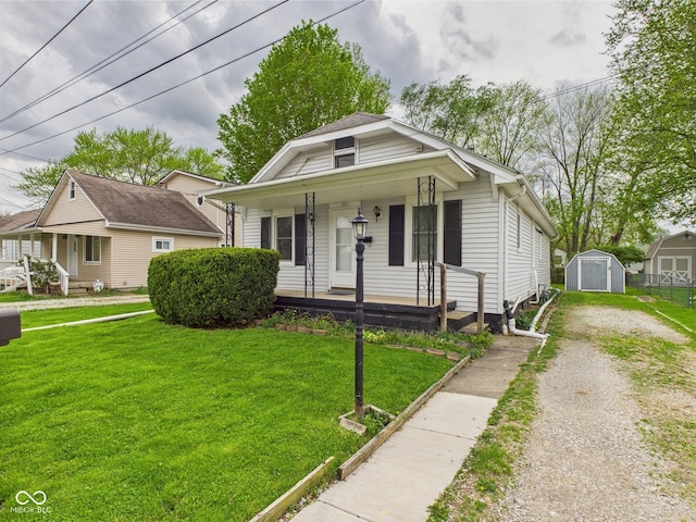 bungalow-style house with a storage unit, an outdoor structure, a porch, and a front lawn