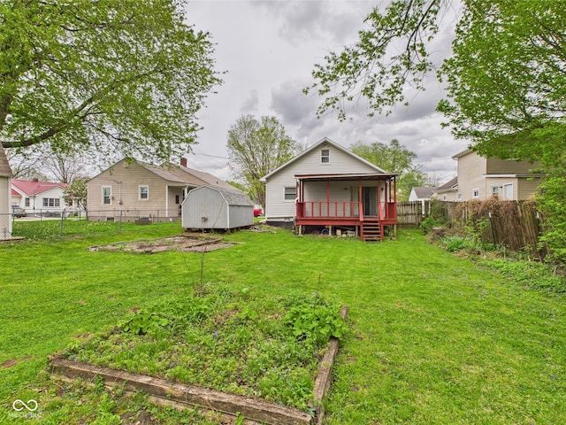 back of property featuring a garden, a storage shed, a lawn, an outbuilding, and a fenced backyard