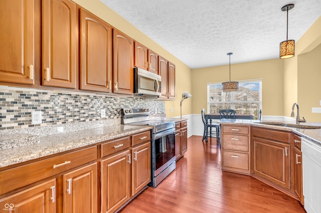 15329 Smithfield Dr, Westfield, IN 46074 - kitchen featuring appliances with stainless steel finishes, a sink, a textured ceiling, decorative light fixtures, and wood finished floors
