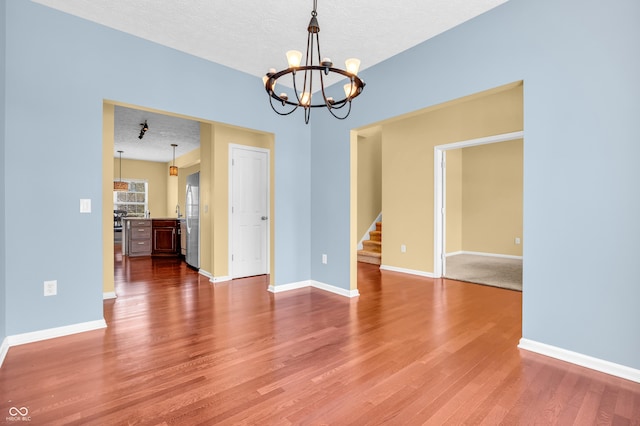 15329 Smithfield Dr, Westfield, IN 46074 - spare room featuring a notable chandelier, a textured ceiling, stairs, baseboards, and wood finished floors