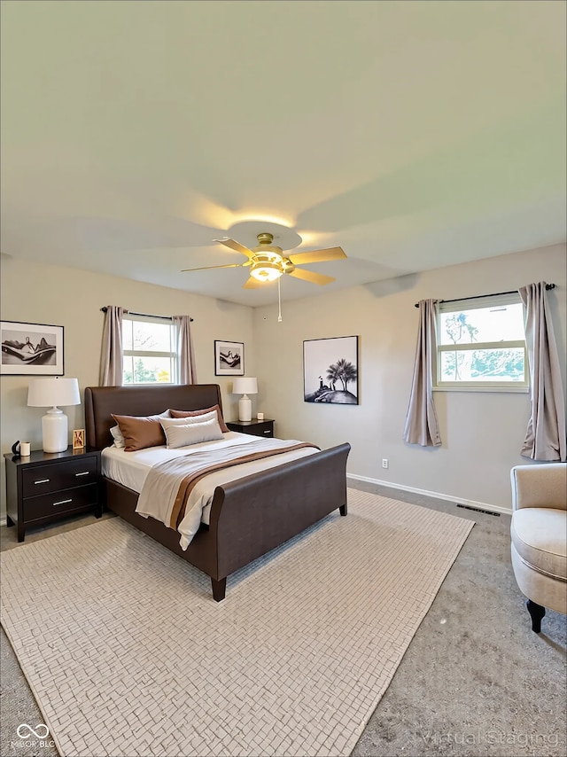 bedroom featuring baseboards, a ceiling fan, multiple windows, and light colored carpet