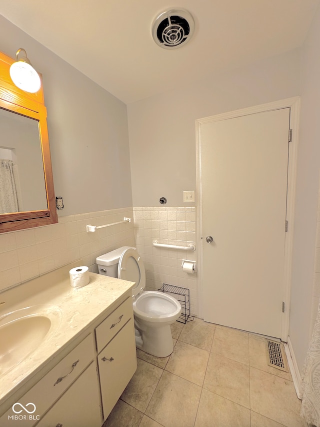 full bath featuring tile patterned flooring, vanity, wainscoting, toilet, and tile walls