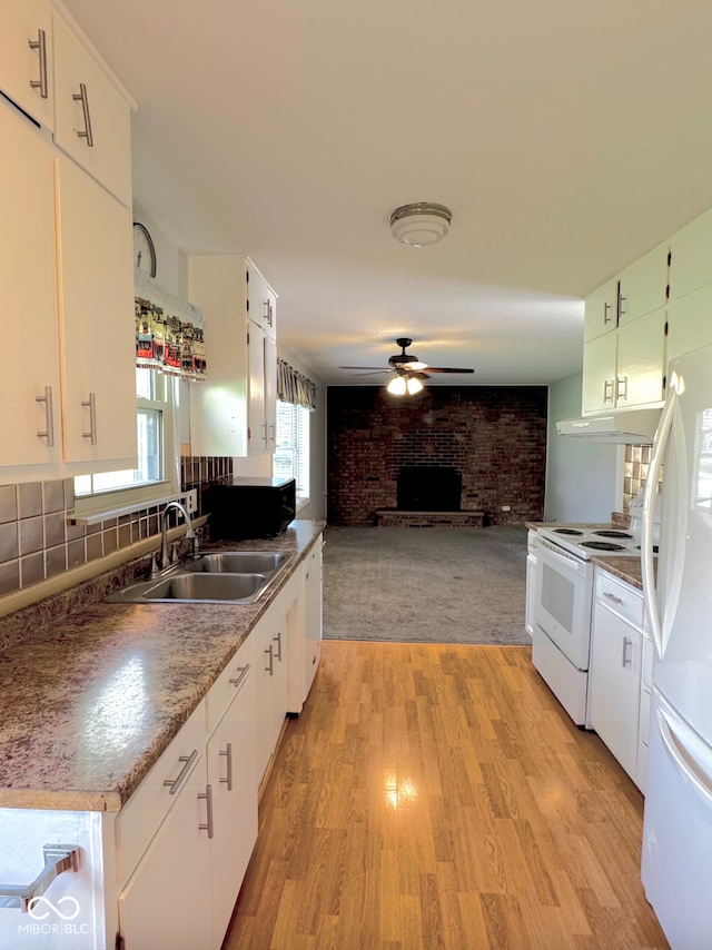 kitchen featuring ceiling fan, a sink, light wood-style floors, white appliances, and a brick fireplace