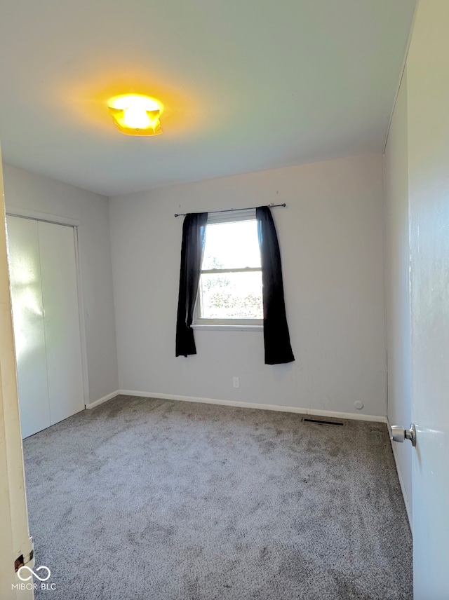 spare room featuring carpet floors, baseboards, and visible vents