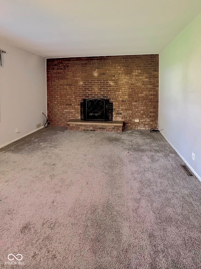 unfurnished living room with visible vents, carpet, a brick fireplace, and baseboards
