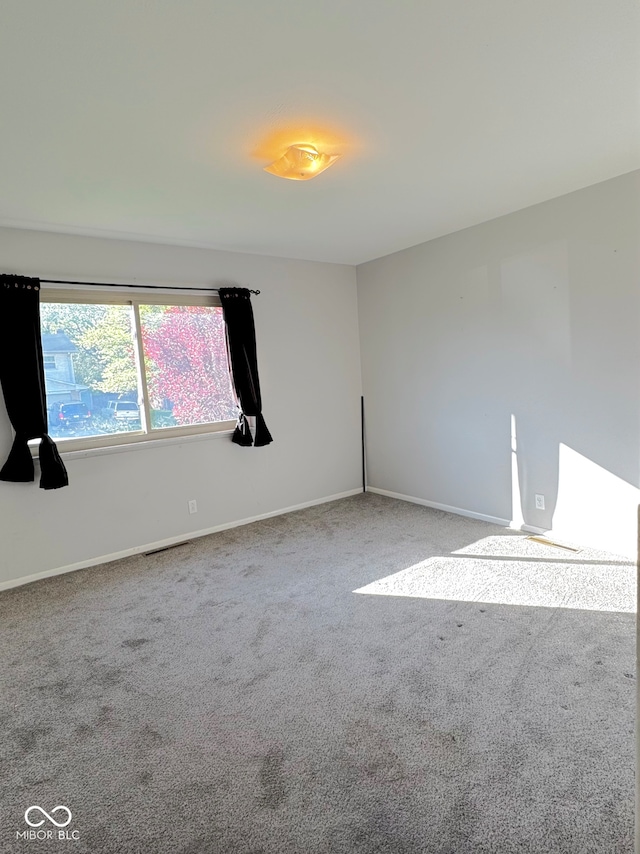 spare room featuring carpet flooring and baseboards
