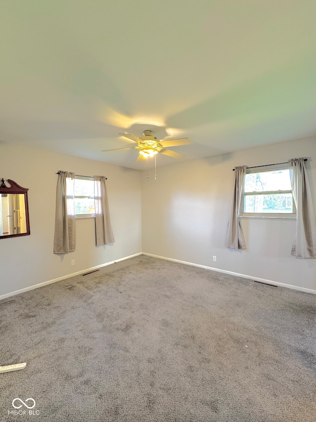 unfurnished room with a healthy amount of sunlight, baseboards, and carpet