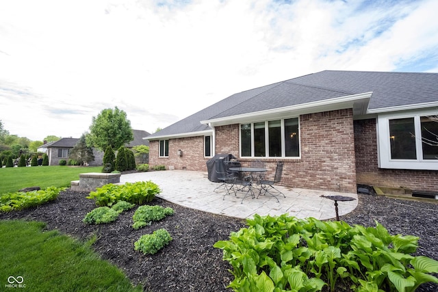 back of house with a lawn, a patio area, brick siding, and a shingled roof
