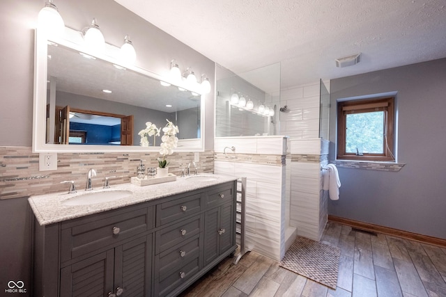 full bath featuring a sink, walk in shower, visible vents, and wood finished floors