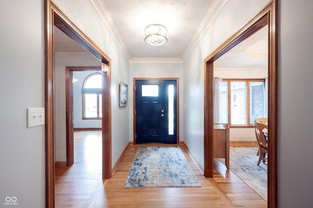entryway featuring light wood finished floors, an inviting chandelier, baseboards, and ornamental molding