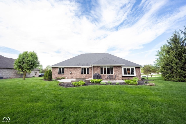 rear view of house featuring a yard, a patio, and brick siding