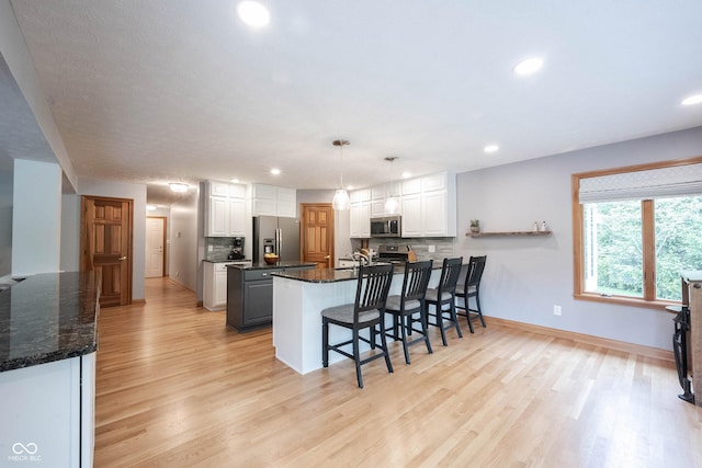 kitchen with a peninsula, light wood finished floors, stainless steel appliances, white cabinets, and recessed lighting