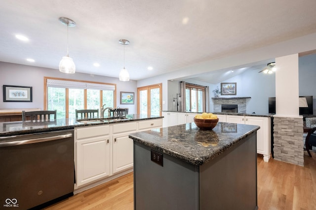 kitchen featuring dishwasher, a sink, a kitchen island, a fireplace, and light wood-type flooring