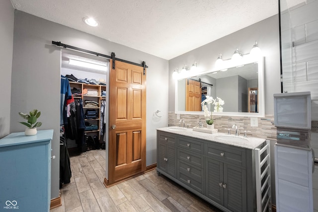 full bath featuring double vanity, decorative backsplash, wood finished floors, and a sink