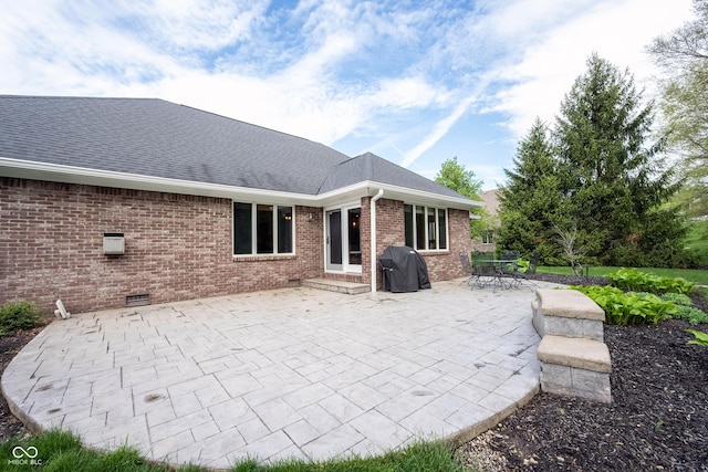 rear view of house with a patio area, brick siding, and a shingled roof