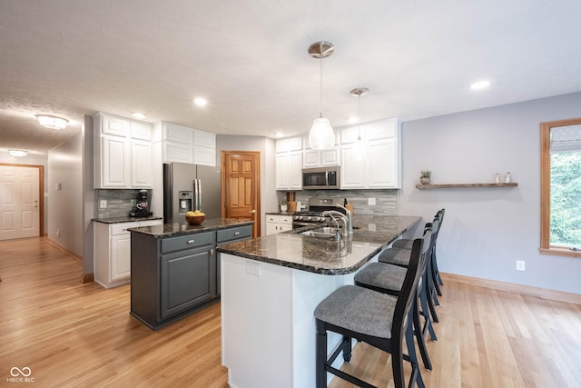 kitchen featuring light wood finished floors, white cabinets, appliances with stainless steel finishes, and a kitchen island