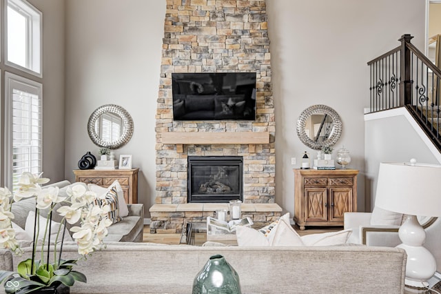 living room with a towering ceiling, stairway, and a fireplace
