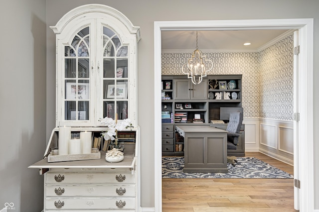 office area featuring crown molding, wainscoting, light wood-type flooring, an inviting chandelier, and wallpapered walls