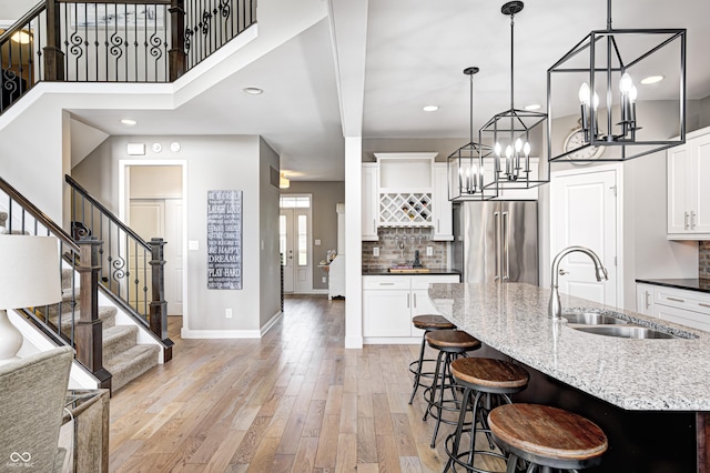 kitchen with a breakfast bar, baseboards, high quality fridge, a sink, and backsplash