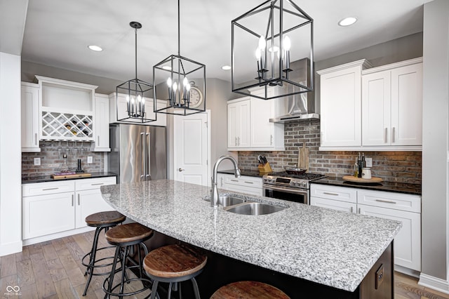 kitchen with a breakfast bar area, a kitchen island with sink, appliances with stainless steel finishes, a sink, and a chandelier