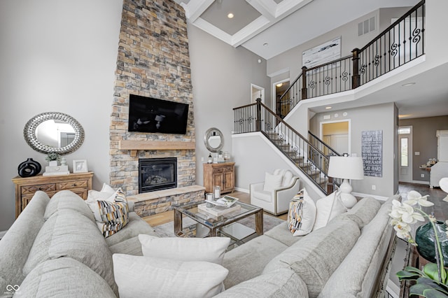 living area with visible vents, a towering ceiling, wood finished floors, stairway, and baseboards