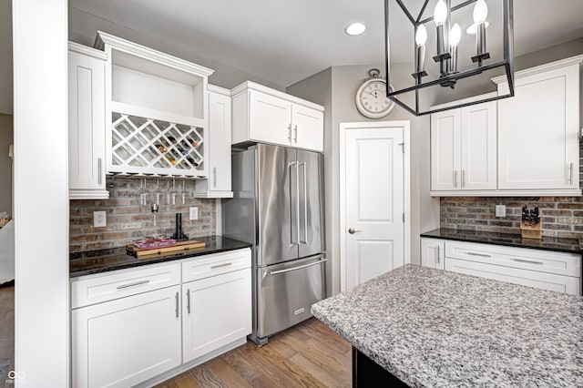 kitchen with tasteful backsplash, light wood-type flooring, dark stone countertops, and high end fridge