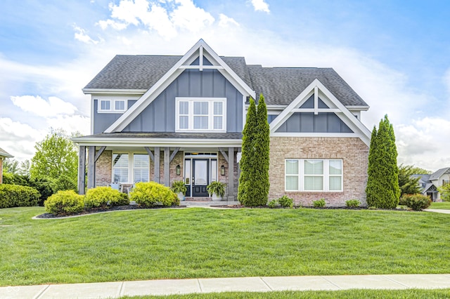 craftsman inspired home with brick siding, a shingled roof, a front lawn, and board and batten siding