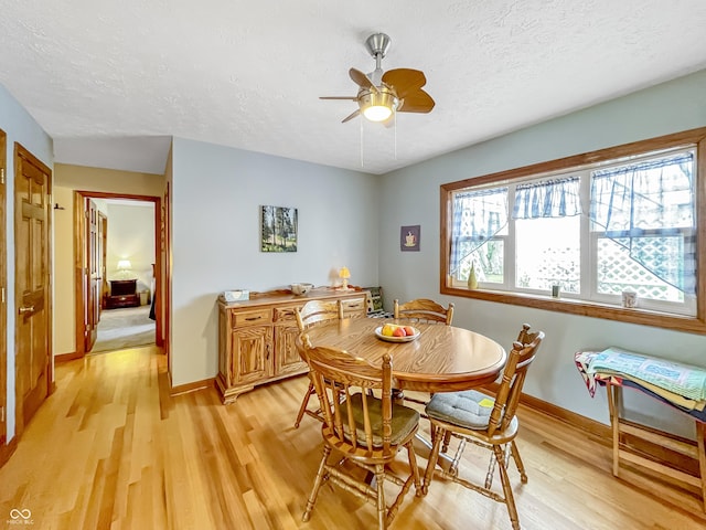 dining room with light wood-type flooring, a textured ceiling, and baseboards