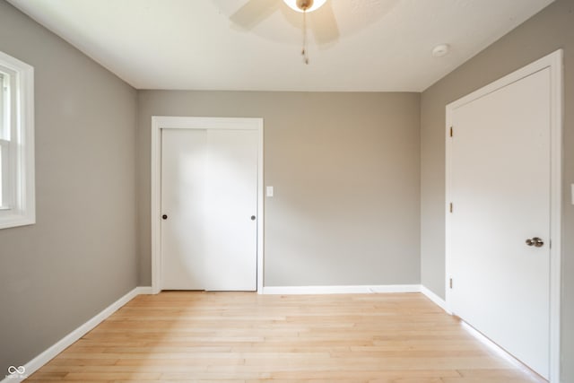 unfurnished bedroom featuring baseboards, ceiling fan, a closet, and light wood-type flooring