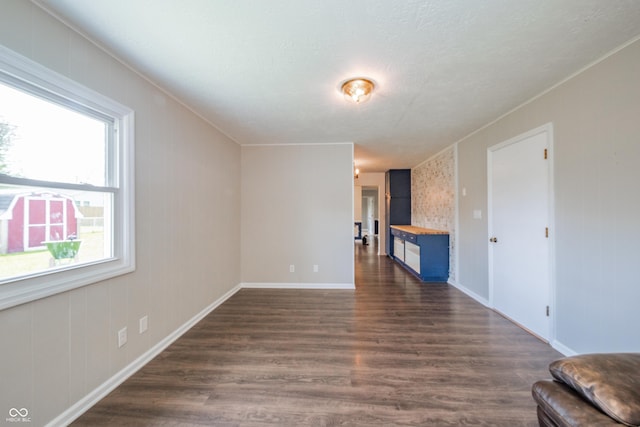 unfurnished living room featuring dark wood-style flooring and baseboards