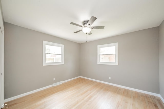 spare room featuring visible vents, a ceiling fan, a wealth of natural light, and light wood-type flooring
